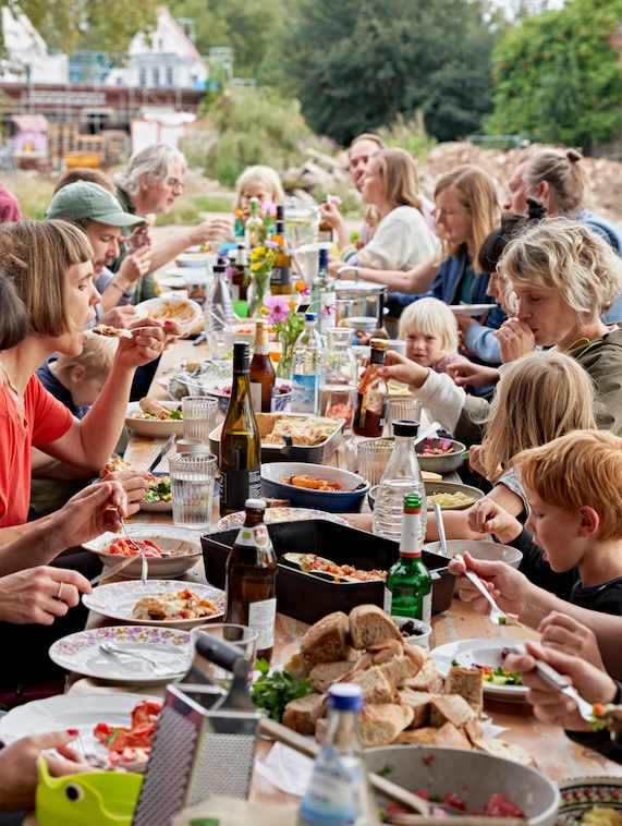 Eine Gruppe von Menschen isst an einem langen Tisch im Freien