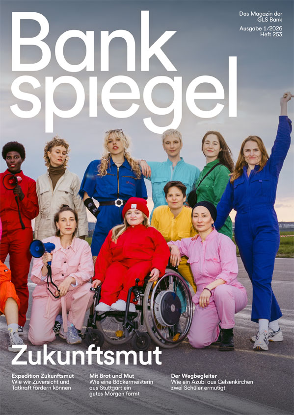 Zwölf Menschen in bunten Overalls posieren an einem bewölkten Tag selbstbewusst im Freien.
