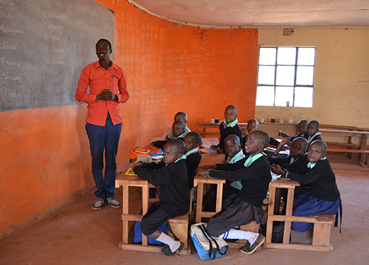 Schüler*innen und Lehrer in einem Klassenzimmer in Kenia