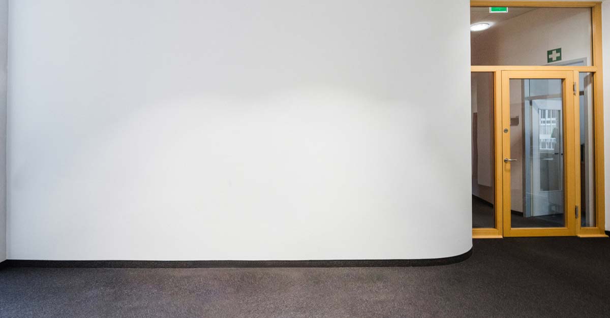 Mach mit bei unserem Kunstwettbewerb "Jetzt // Gestalten" Leere weiße Wand in einem Bürogebäude