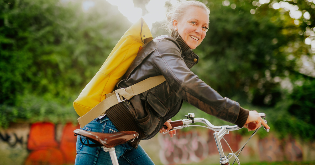 Stadtradeln 2024 Eine Frau mit gelben Rucksack steigt auf ihr Fahrrad.