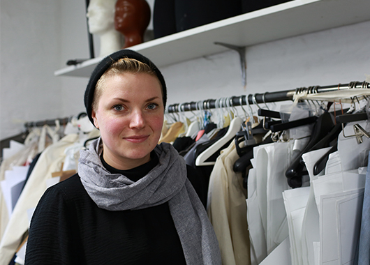 Junge Frau steht in einem Geschäft vor einer Kleiderstange