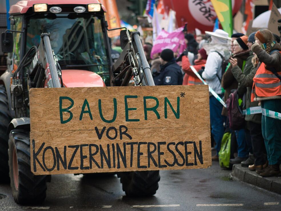 Traktor mit Schild: Bauern* vor Konzerninteressen