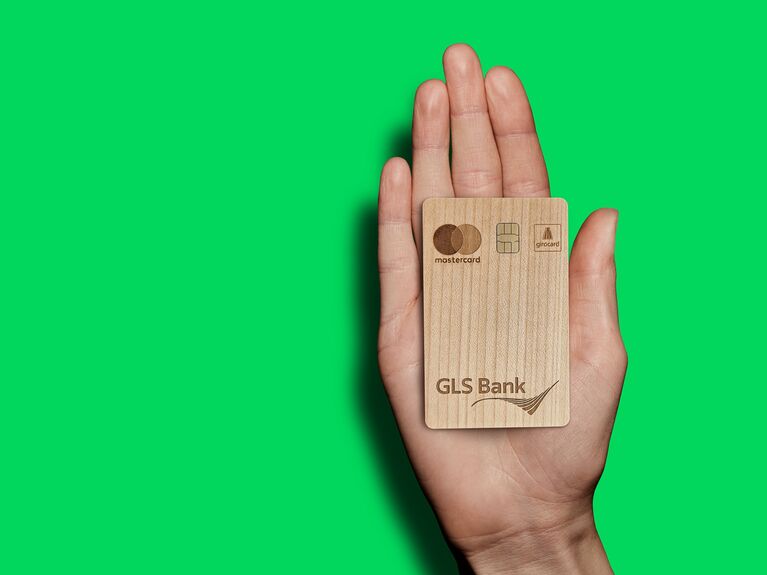 Hand mit GLS Bankkarte aus Holz. Dieses Bild wurde KI generiert.