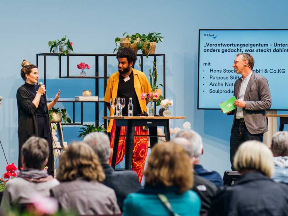 4 Menschen auf der Buehne beim GLS Juilaeumsfestival. Thema: Verantwortungseigentum