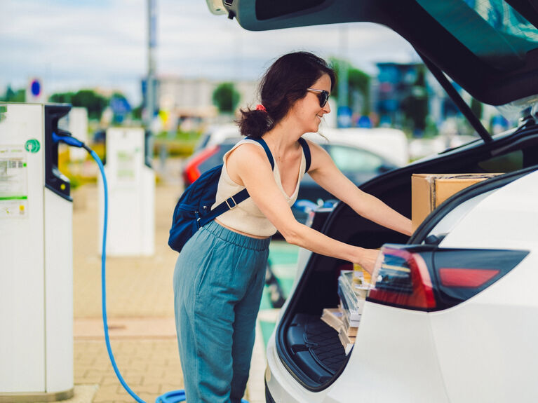 Frau lädt Kisten in den Kofferraum ihres Elektroautos ein