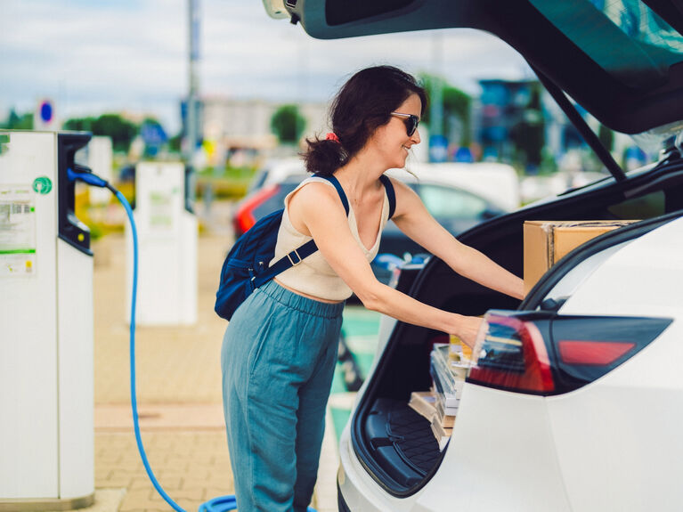 Frau lädt Kisten in den Kofferraum ihres Elektroautos ein