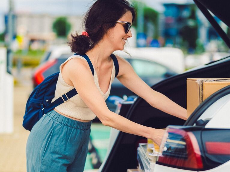 E-Auto mit der GLS Bank finanzieren Frau lädt Kisten in den Kofferraum ihres Elektroautos ein