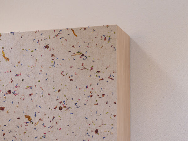 Nahaufnahme einer strukturierten Wandverkleidung mit bunten Sprenkeln neben einer schlichten weißen Wand.