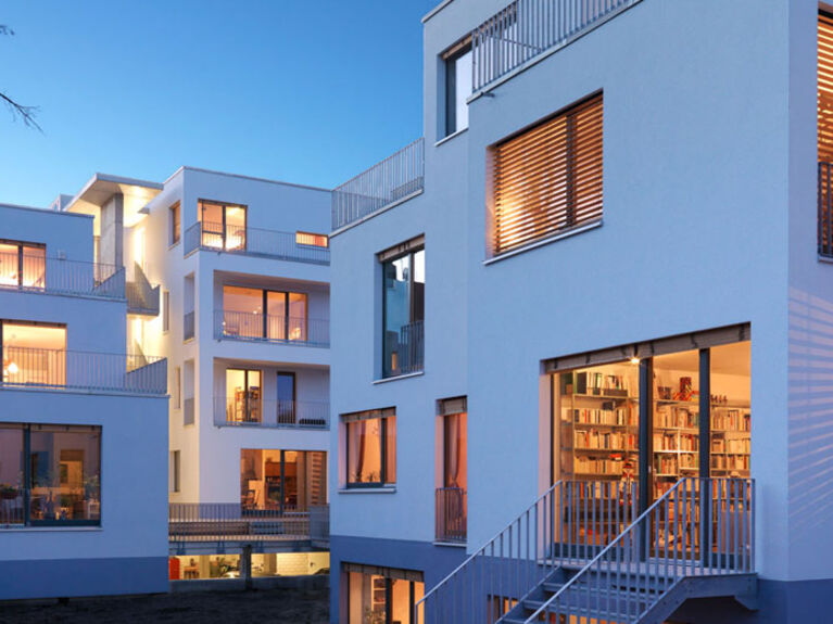 Außenansicht von Mehrfamilien-Wohnungen mit erleuchteten Fenster in der Dämmerung