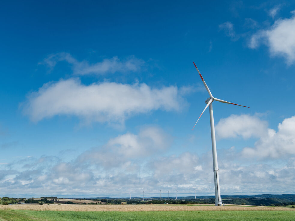 Windkraftanlage auf einer Wiese mit blauem Himmel.