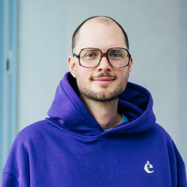 Eine junge männlich gelesene Person mit Brille und Hoodie.