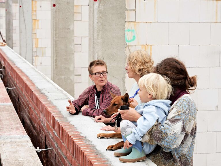 3 weiblich gelesene Personen und ein Kleinkind auf einer Baustelle