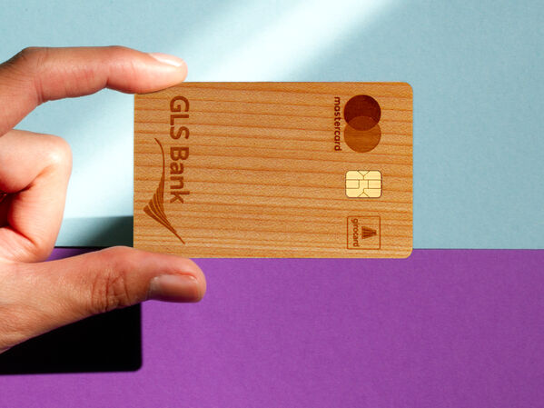 Holzkarte der GLS Bank vor zweifarbigem Hintergrund