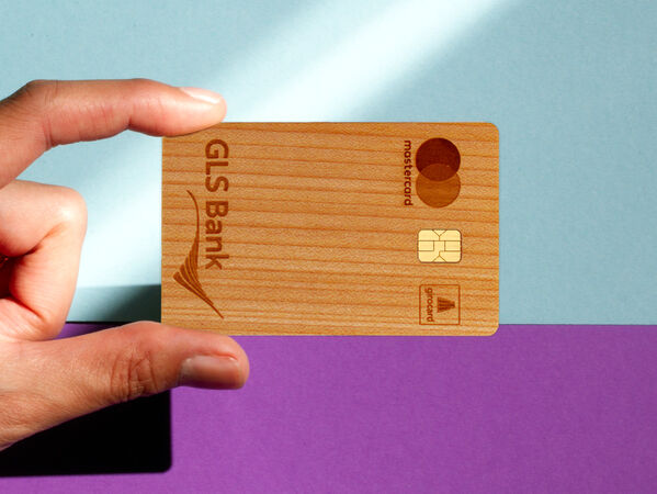 Holzkarte der GLS Bank vor zweifarbigem Hintergrund