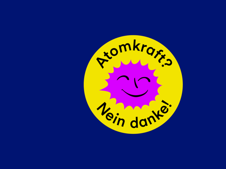 Gelbe Plakette mit einer rosa lächelnden Sonne und dem Text Atomkraft? Nein danke.