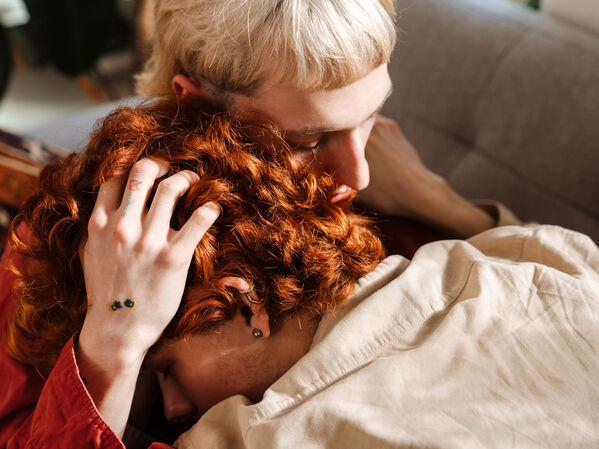 Zwei junge queer gelesene Menschen halten sich am Kopf.