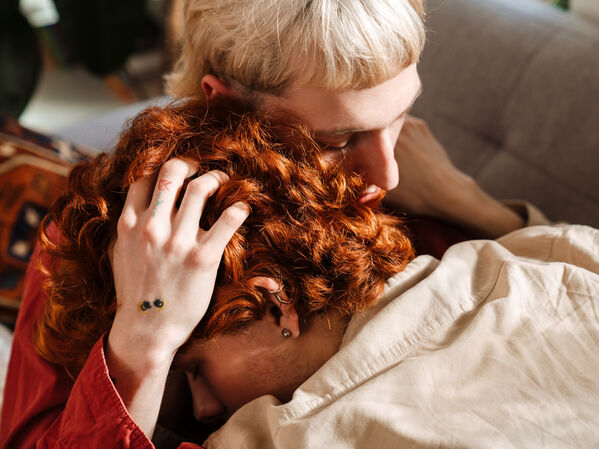 Zwei junge queer gelesene Menschen halten sich am Kopf.