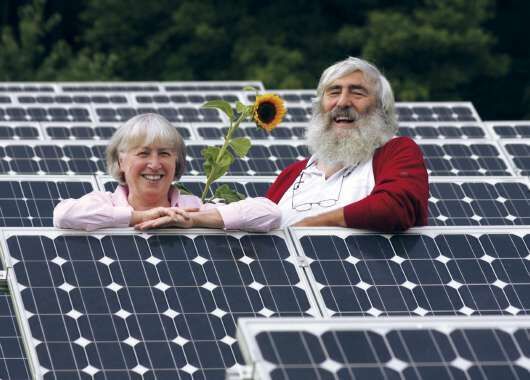Zwei Menschen stehen auf einer Solaranlage - EWS Schönau, finanziert von der GLS Bank