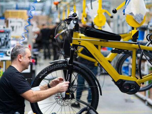 Männlich gelesen Person arbeitet an einem Fahrrad im Fahrradshop.