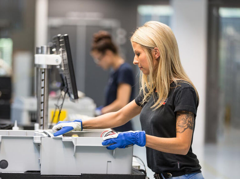 Weiblich gelesene Person an einer Maschine