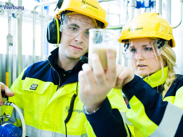 Eine Frau und ein Mann mit Schutzausrüstung und einem Reagenzglas