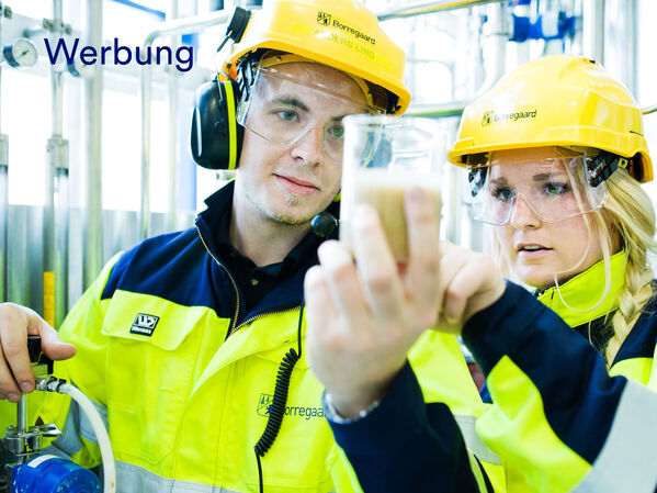 Eine Frau und ein Mann mit Schutzausrüstung und einem Reagenzglas