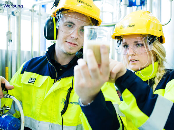 Eine Frau und ein Mann mit Schutzausrüstung und einem Reagenzglas