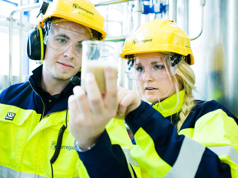 Eine Frau und ein Mann mit Schutzausrüstung und einem Reagenzglas