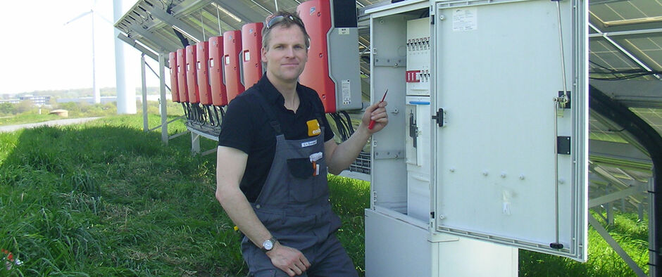 Mann am Wechselrichter einer großen Photovoltaik-Anlage.