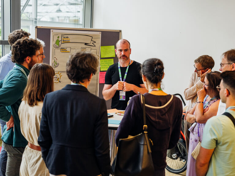 Ein Mann spricht während eines Workshops in einem hell erleuchteten Konferenzraum zu einer Gruppe.