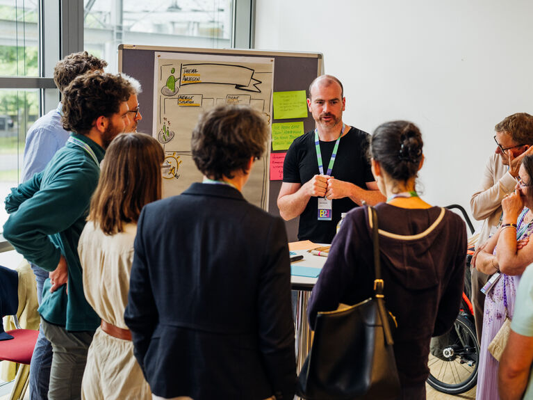 Ein Mann spricht während eines Workshops in einem hell erleuchteten Konferenzraum zu einer Gruppe.