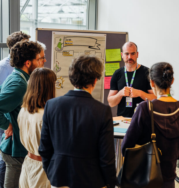 Ein Mann spricht während eines Workshops in einem hell erleuchteten Konferenzraum zu einer Gruppe.