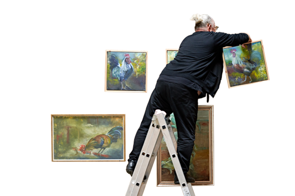 Mann hängt mit einer Leiter Bilder im Hof Prädikow auf.