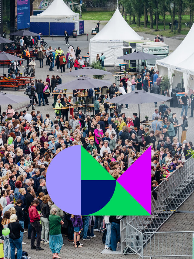 Große Menschenmenge bei einem Festival im Freien mit Zelten und der Aufschrift Gutes Morgen Festival.