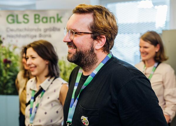 Die Menschen bei der GLS Bank kannst du bei Veranstaltungen kennenlernen Drei Gäste mit guter Laune bei einer GLS Veranstaltung