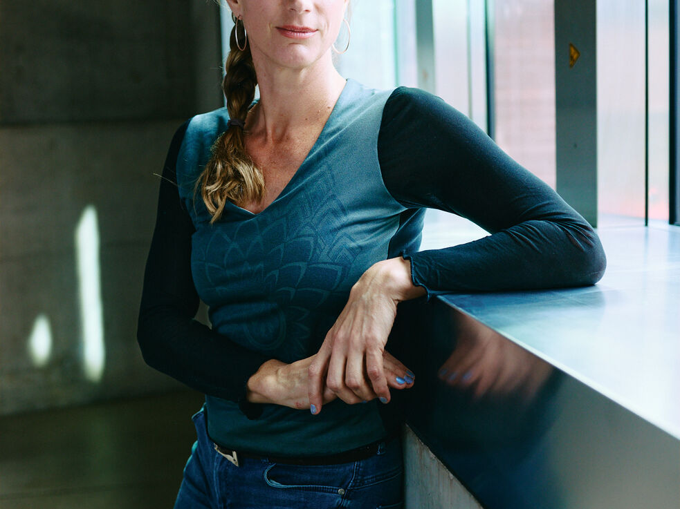 Maja Göpel lehnt an einer Fensterbank in einem modernen Gebäude.