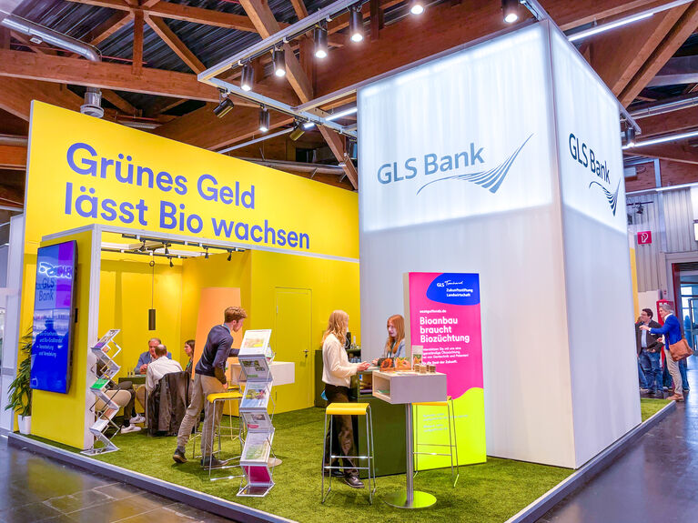 GLS Messestand mit Plakat "Grünes Geld lässt Bio wachsen"