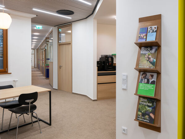 Büroraum mit Halterung aus Holz an einer Wand für Flyer und Magazine.