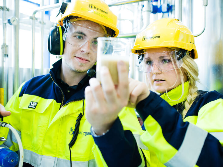 Eine Frau und ein Mann mit Schutzausrüstung und einem Reagenzglas