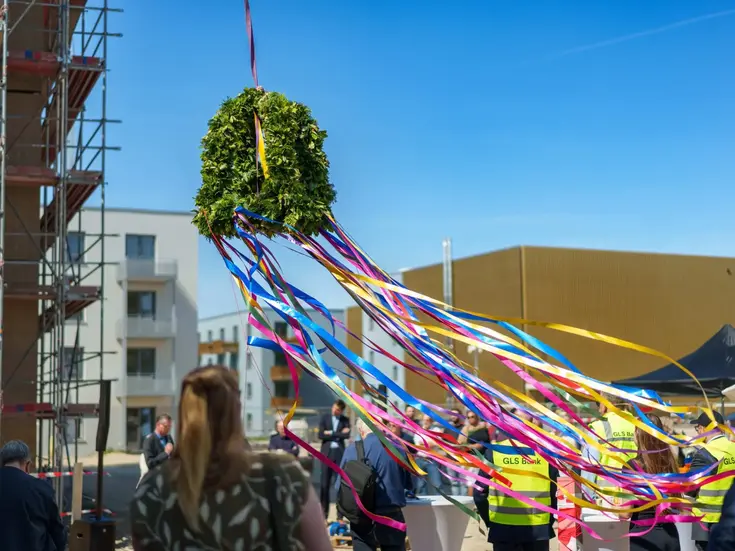 Richtfest mit Richtkrone aus Zweigen, bunten Bändern und Menschen