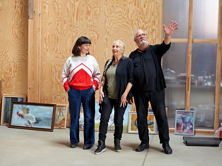 Zwei Frauen und ein Mann stehen in einer Ausstellung und schauen sich um.