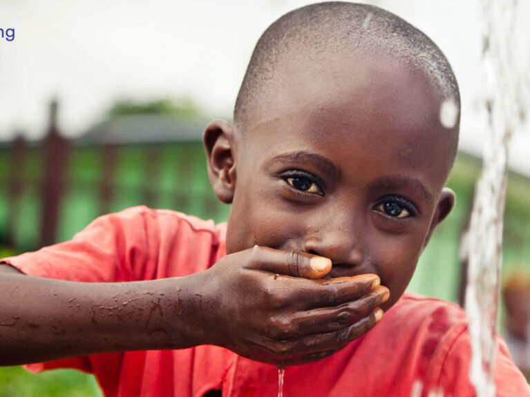 Afrikanisches Kind trinkt an einer Wasserleitung Wasser aus der Hand