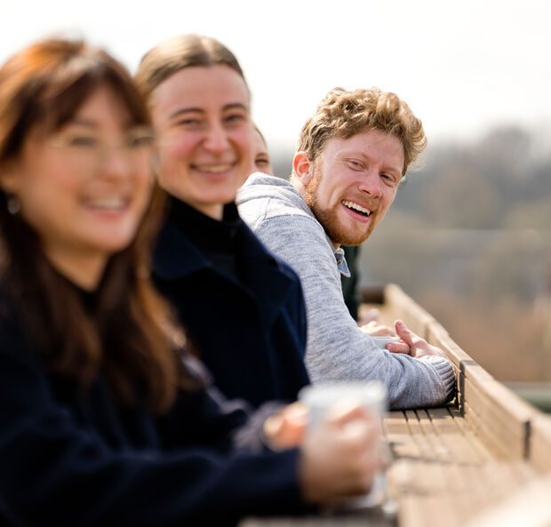 Drei lachende Menschen auf einem Ausichtspunkt.