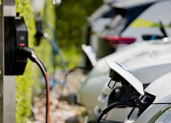 Ein helles Elektroauto an einer Aufladestation.