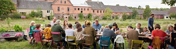 Menschengruppe feiert an einer langen Tafel im Garten von Hof Prädikow.