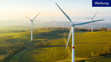Mehrere Windkraftanlagen stehen auf grasbewachsenen Hügeln. Hinweis: Werbung