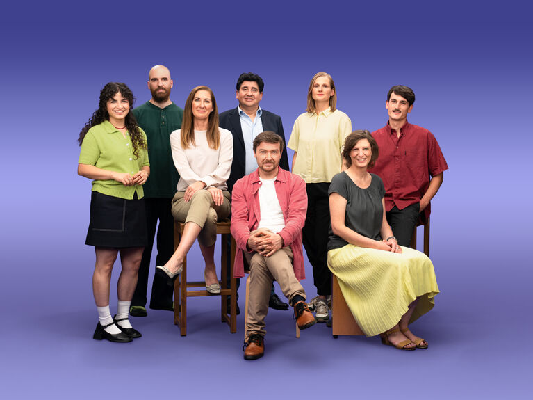 Gruppenfoto von 8 GLS Kund*innen vor einem lila Hintergrund