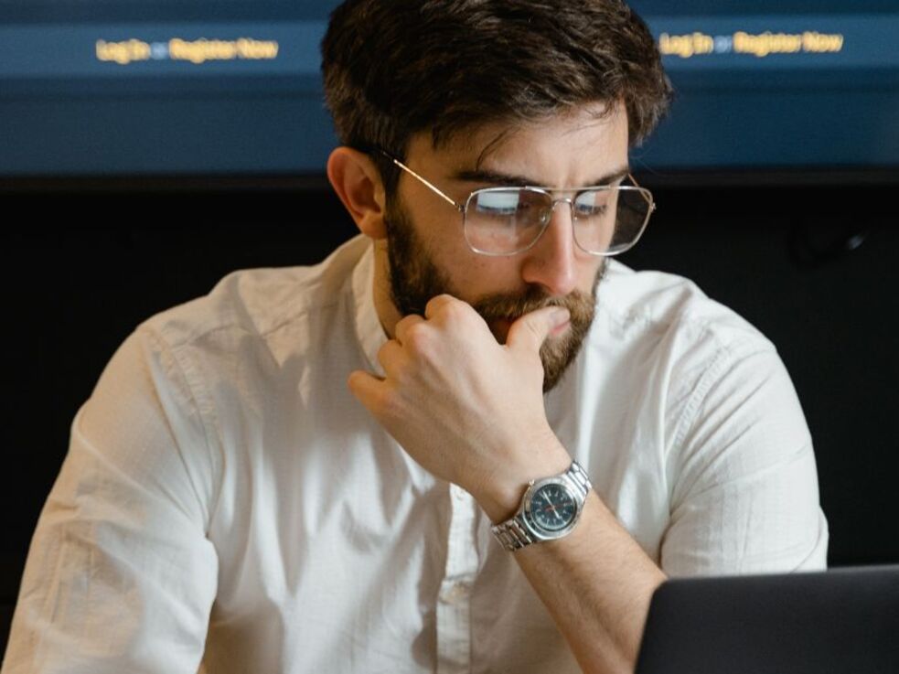 Mann am Laptop und im Hintergrund ein Daten-Dashboard