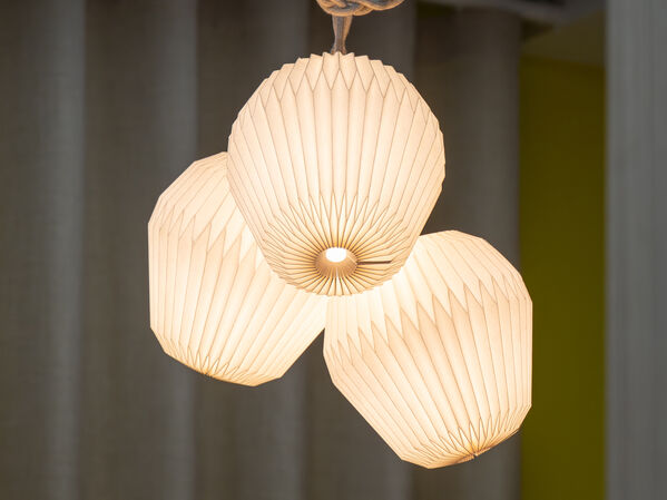 Eine Lampe mit drei Leuchtkörpern aus Papier hängend von der Decke an einer Schnur.